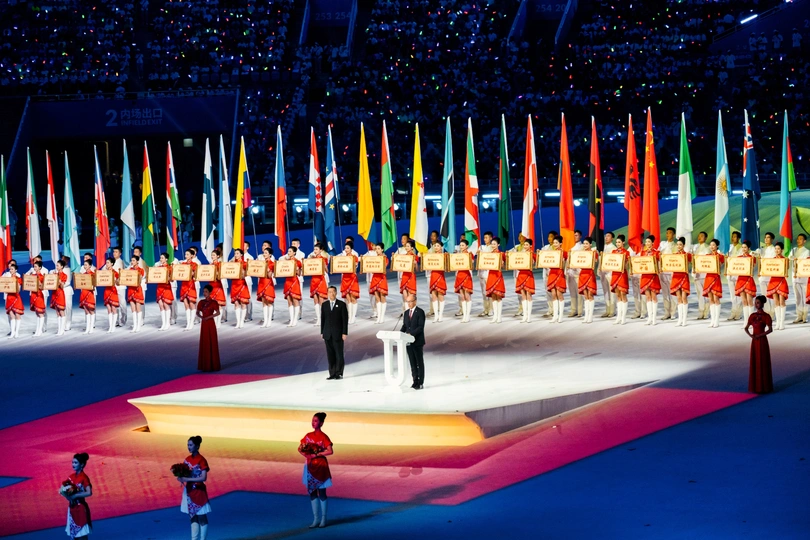 表演者在一场文化活动中站在不同颜色旗帜的彩色舞台上。