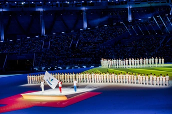 表演者们在开幕式上站在场地 挥舞着国旗。