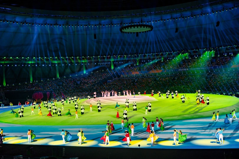 表演者与舞者在一场表演期间在大型体育场跳舞。