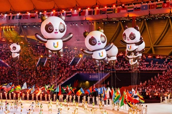 表演者手持国旗和气球在一个大型观众面前的舞台上表演。