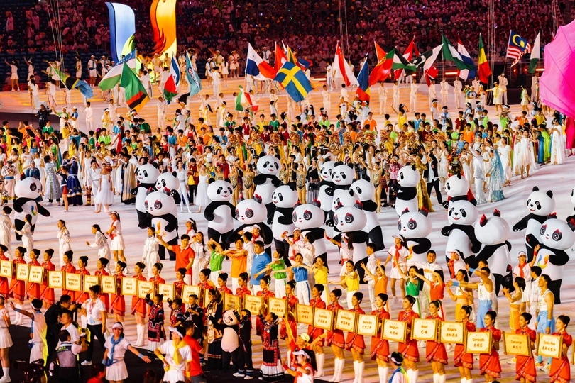 很多人站在一群熊猫的前面