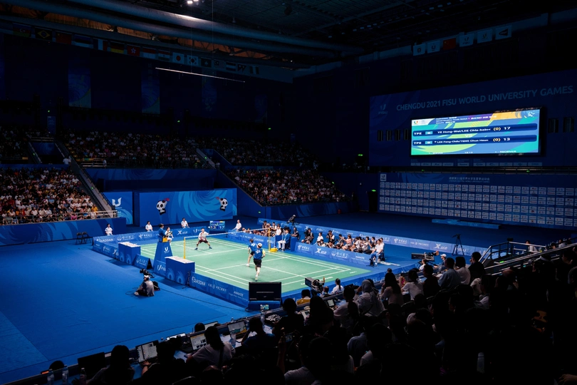 许多人观看一场网球比赛在蓝色的网球场 球员在室内体育馆进行比赛。