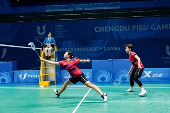 一个男子和一个女子在一个网球场打羽毛球。