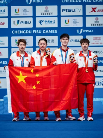 男子团队运动员在领奖台上手持红旗拍照