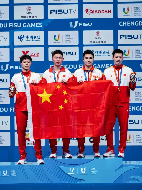 男子团队运动员在领奖台上举着金牌和红旗