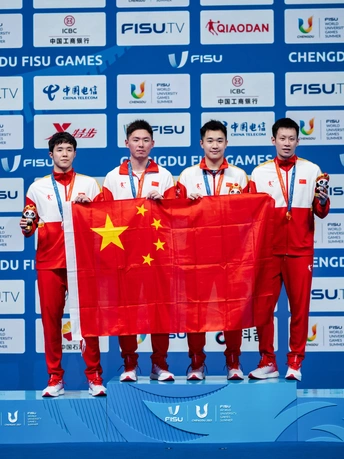 男子团队运动员在领奖台上举着金牌和红旗