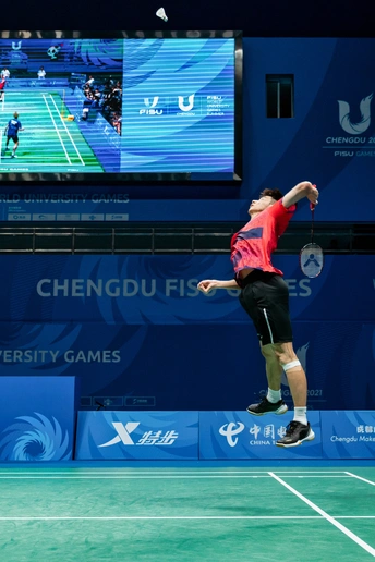 一个穿红衬衫和黑色短裤的男子在网球场打网球 手握网球拍和网球。