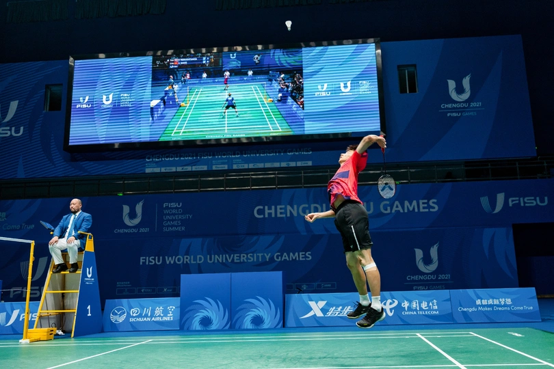 网球场上 一个人在打网球 一个人在空中跳跃。