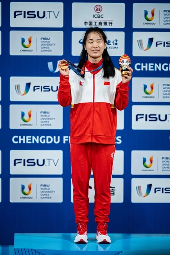 一位女子举着金牌站在领奖台上