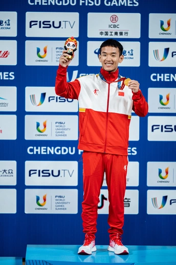 一位男子站在领奖台上 手里拿着一枚金牌。