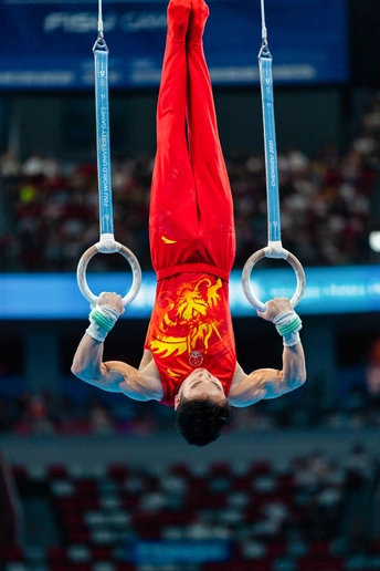 一个男性运动员在进行艺术体操中的吊环表演