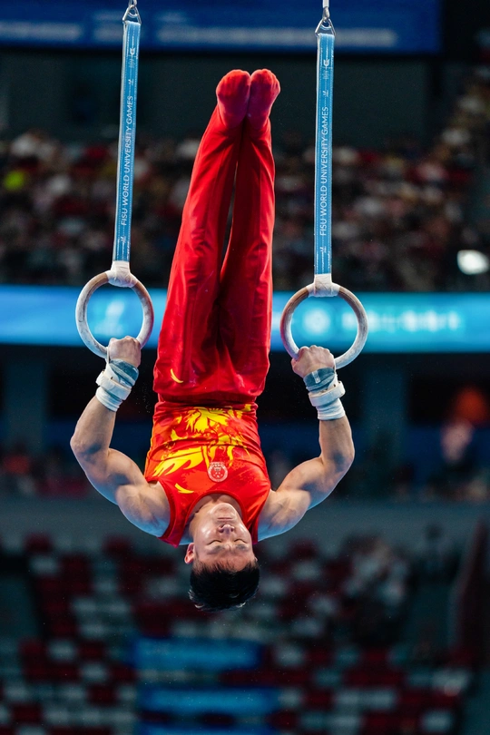 一个男性运动员在艺术体操比赛中在吊环上表演。