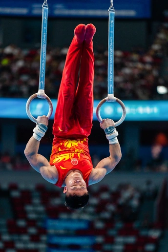 一个男性运动员在艺术体操比赛中在吊环上表演。