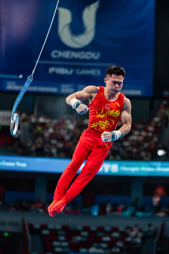 一位男性运动员在比赛中表演吊环