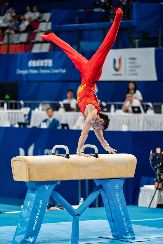 在体操比赛中 一个男子在杆上表演。