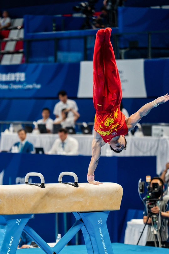 运动员在男子个人全能决赛中在 beam 上表演