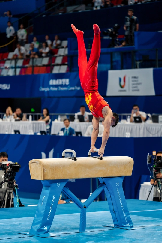 在体操比赛中 一个男子在杆上表演。