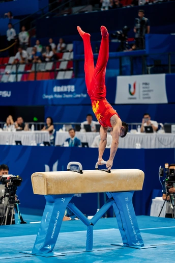 在体操比赛中 一个男子在杆上表演。