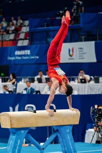 在体操比赛中 一个男子在杆上表演。