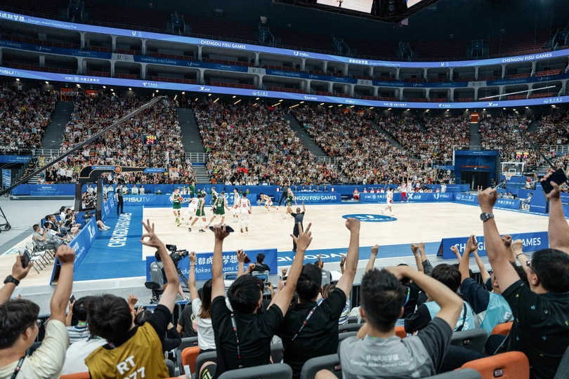 人们在体育馆观看篮球比赛 为他们的队伍欢呼 球场上有篮球比赛在进行。