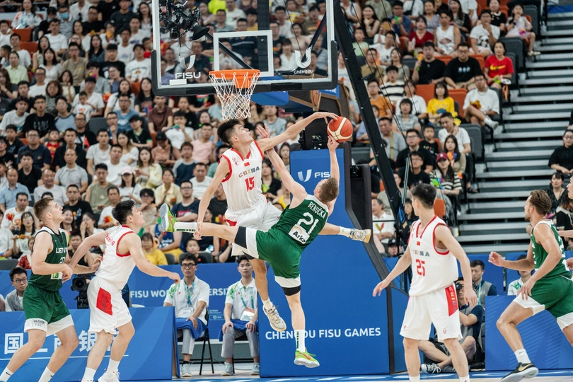 人们在场上打篮球 场边有观众。