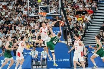 人们在场上打篮球 场边有观众。