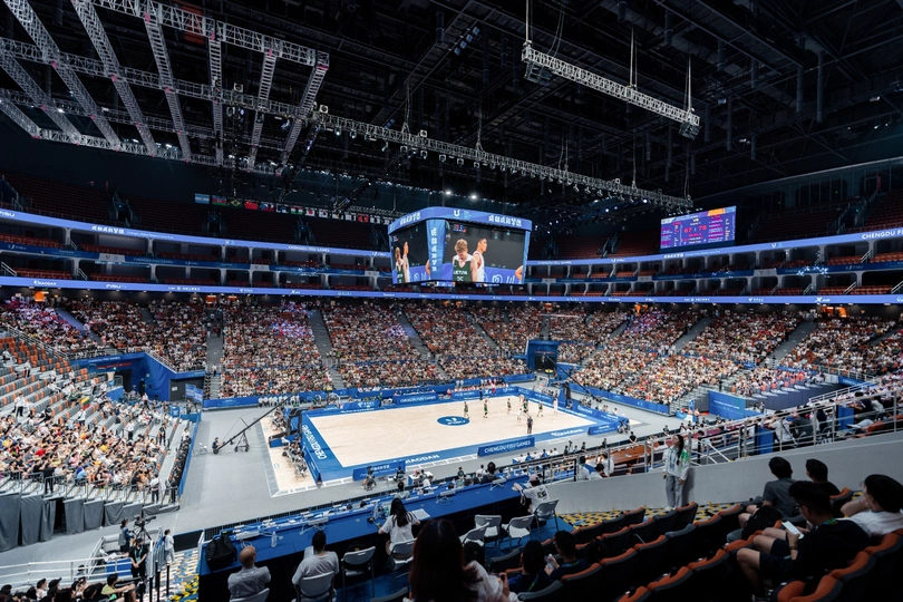 很多人在一个体育馆观看一场篮球比赛。