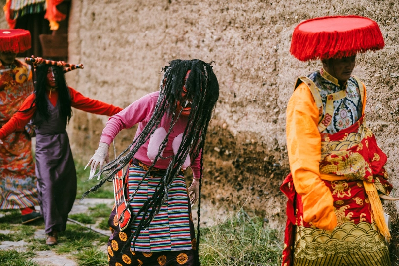 一位头戴红伞的妇女在村庄中行走