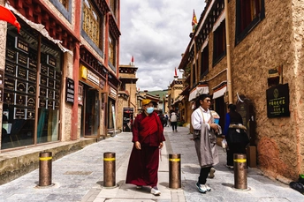 人们在中国一个古老的小镇上走下一条狭窄的街道 前景是一位和尚站在画面中央。