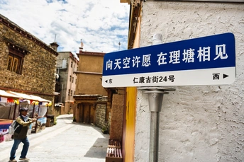 旁边有一栋建筑 有一个蓝色和白色的街道标志