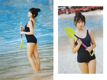 一位年轻的亚洲女性穿着比基尼站在海滩的水中