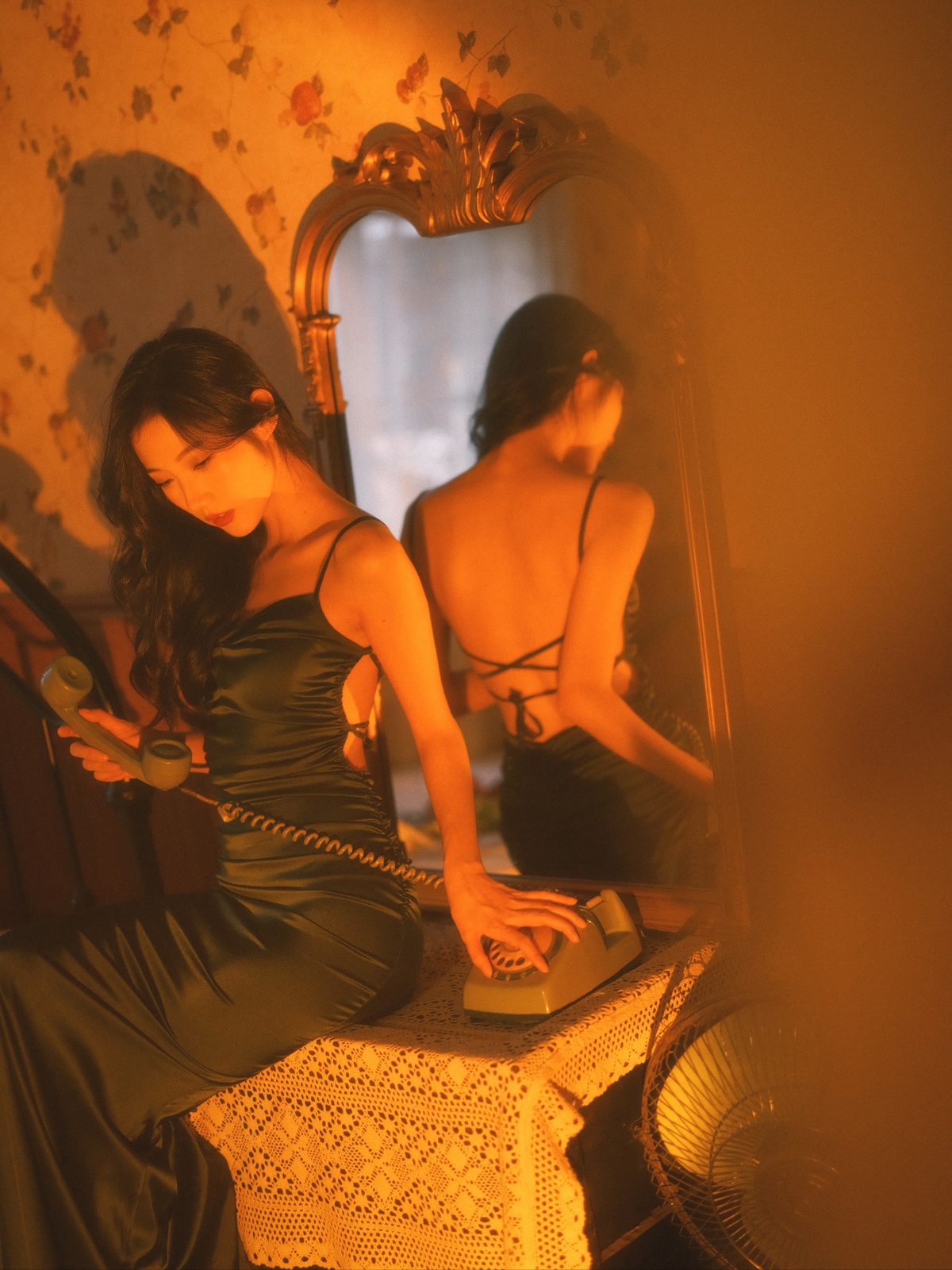 一个穿着黑色连衣裙的年轻女子坐在一个带有镜子的房间里的一张桌子上