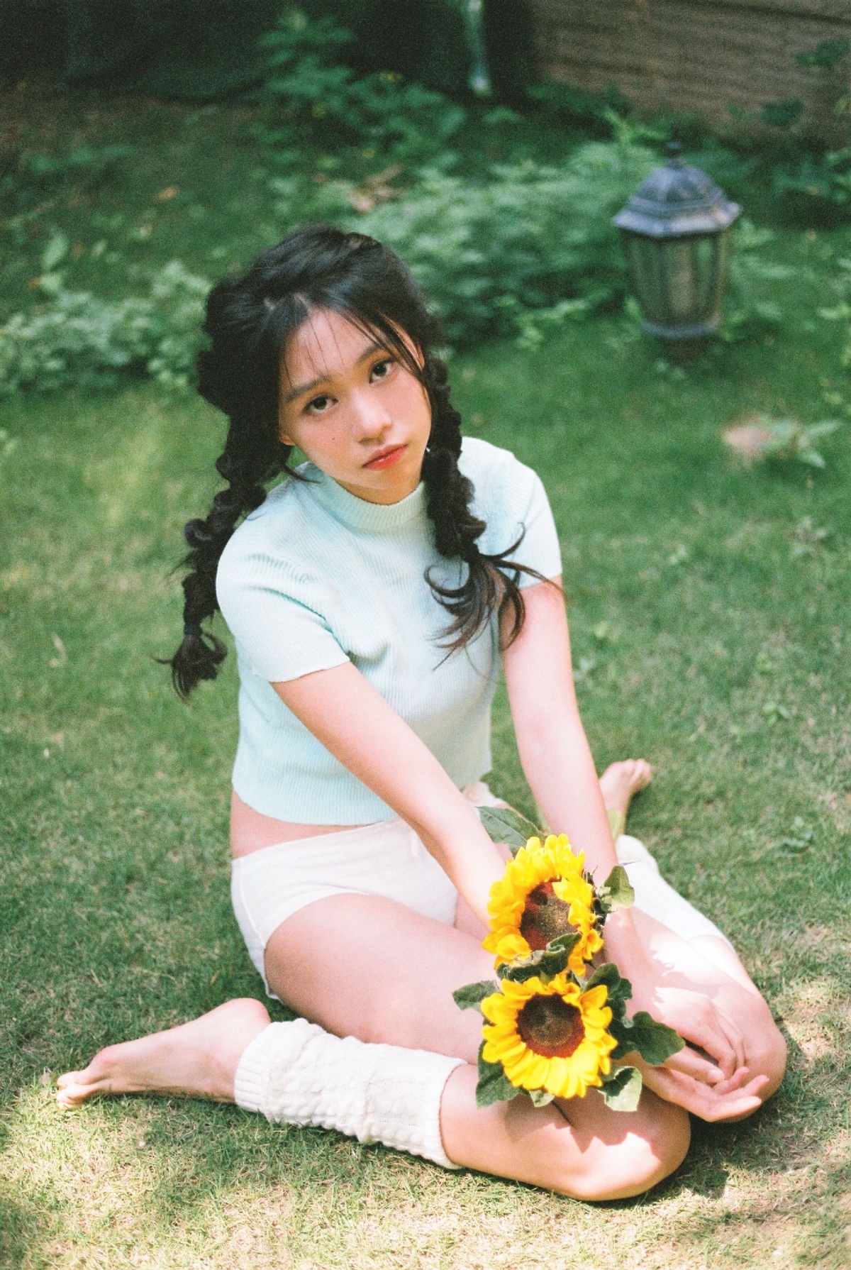一个小女孩坐在后院草地上 草地上有一朵向日葵
