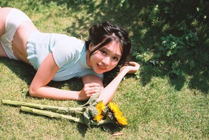 一个年轻女子躺在草地上 手里拿着一束花。