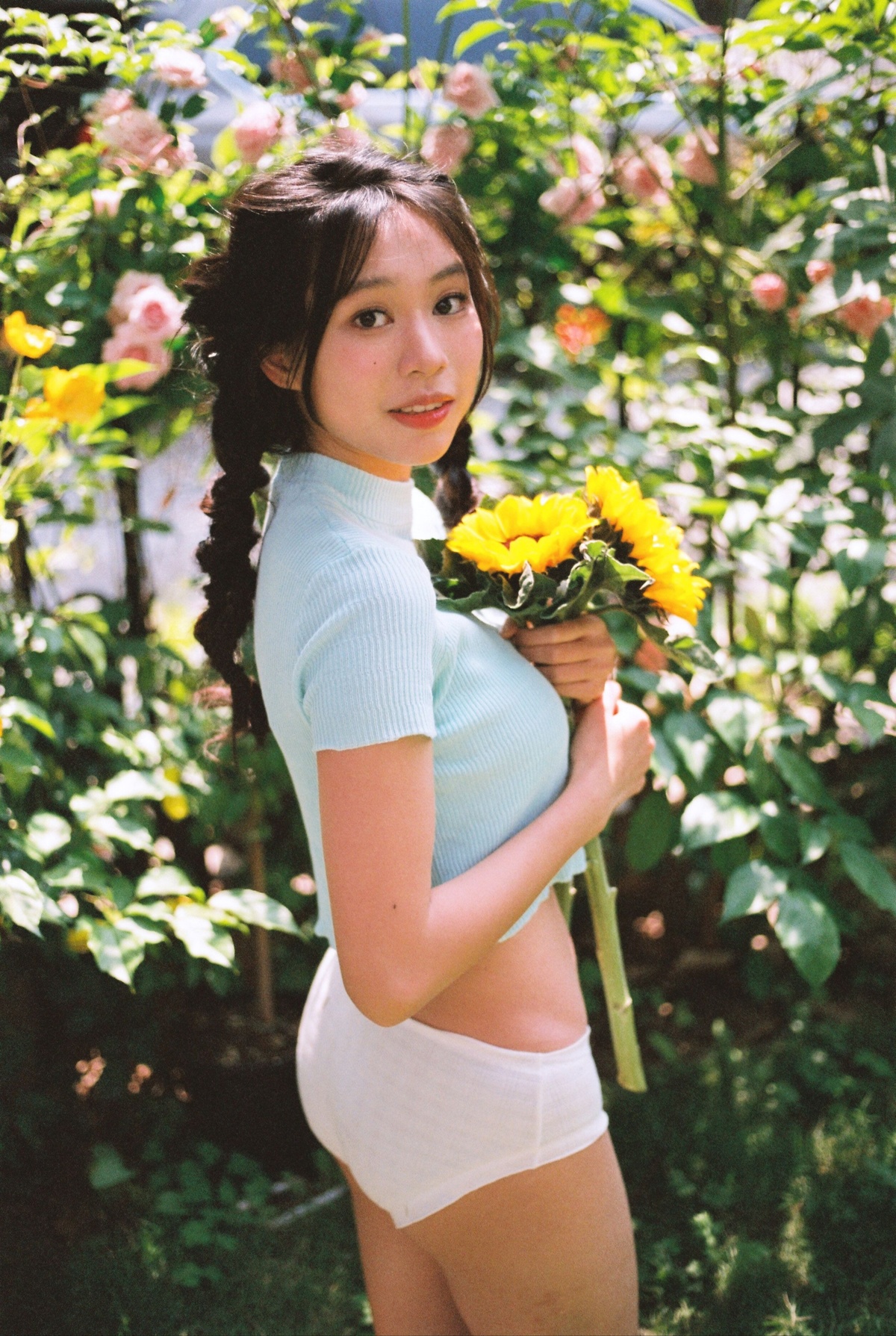 一位年轻女子在花园里拿着黄玫瑰