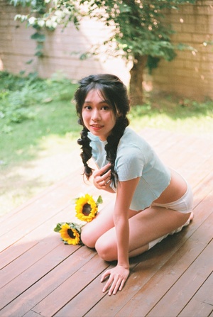 一个年轻女子坐在木甲板上 头戴向日葵