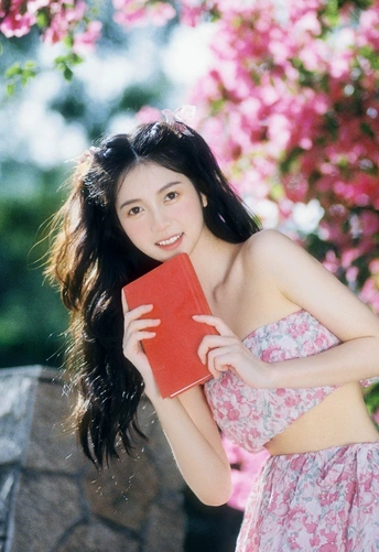 一位穿着花裙子的年轻女子拿着一本红色的书