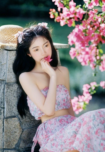 一个坐在粉色花朵旁边长椅上的美丽年轻女子