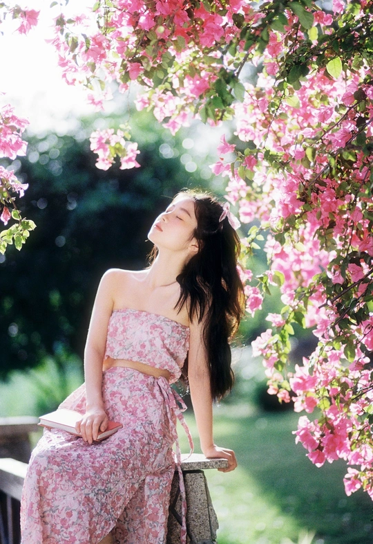 一位穿着花裙子的美丽年轻女子坐在树上