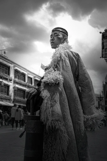一个穿着戏服、拿着水桶和外套走在街上的男人的黑白照片