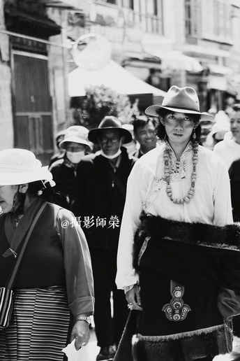 一张黑白照片 一个戴帽子的女人走在街上