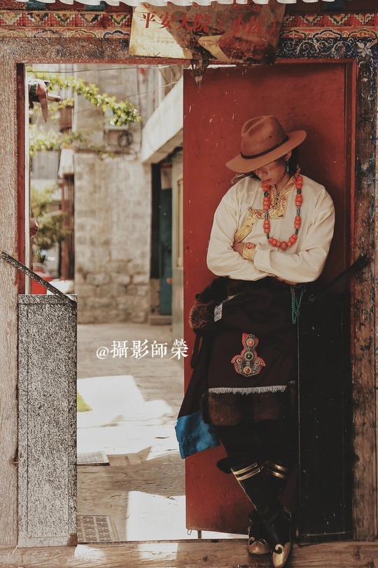 一个戴着牛仔帽的男人靠在一栋大楼的红色门上