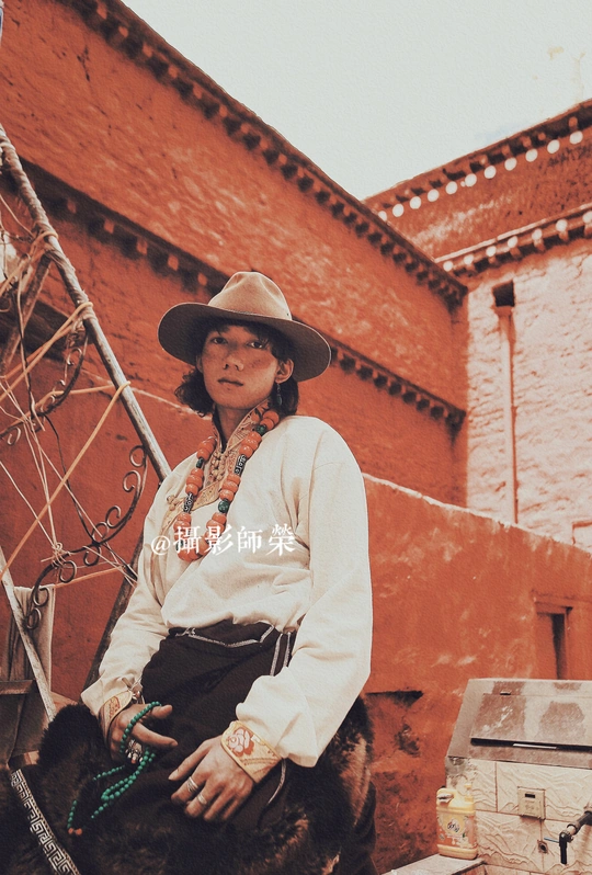 一个戴着帽子的女人坐在一座旧建筑前的马上