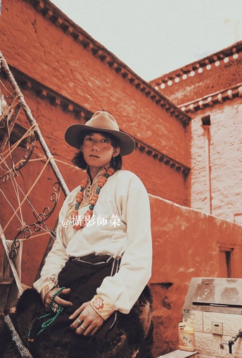 一个戴着帽子的女人坐在一座旧建筑前的马上