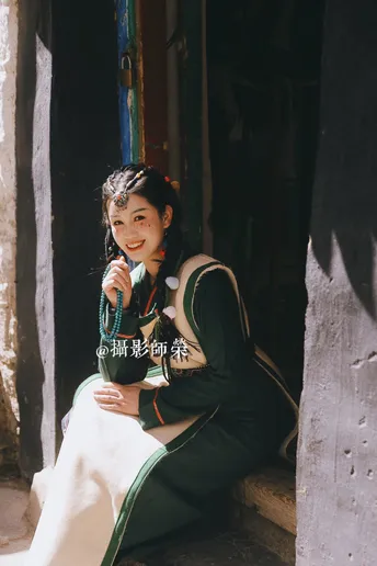一个穿着传统服装的年轻女孩坐在房子的门口