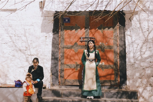 一位妇女和一个孩子站在一栋建筑的台阶上 前面有一个穿服装的女士雕像。