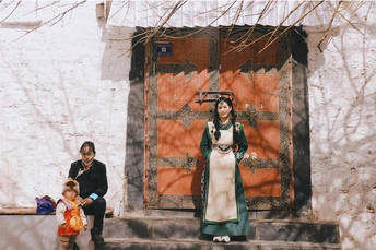 一位妇女和一个孩子站在一栋建筑的台阶上 前面有一个穿服装的女士雕像。