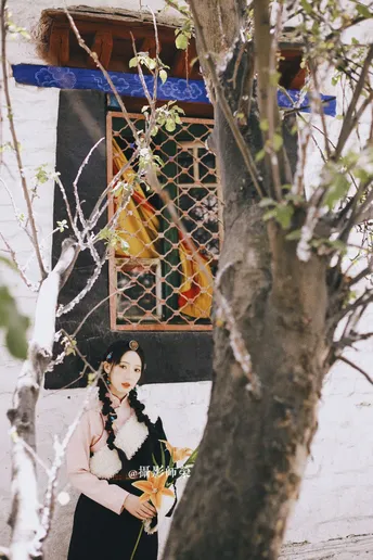 一位穿着传统服装的女孩拿着花站在寺庙前面