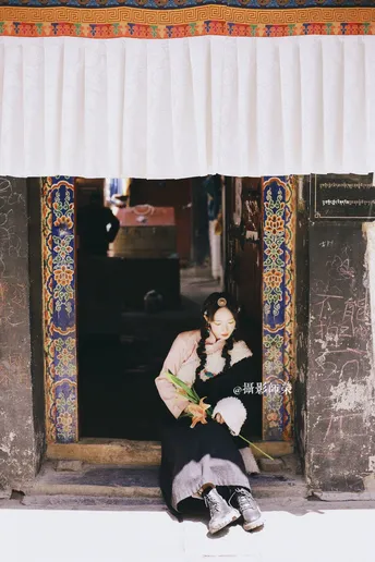 一个年轻女孩坐在一座老建筑里 手里拿着花。