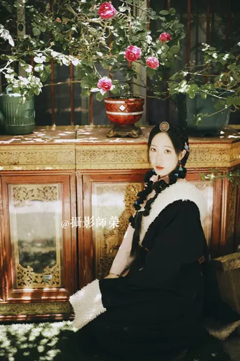 一个穿着黑色连衣裙的女人坐在一个花盆和花前